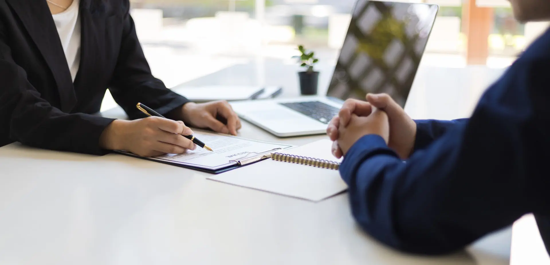 Here's an 8-word alt tag for the image: Businesswoman signing document with client across table.